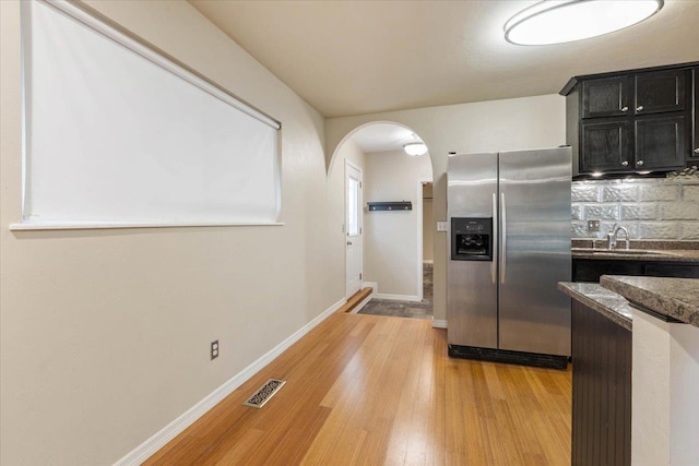 kitchen featuring decorative backsplash, stainless steel fridge, sink, and light hardwood / wood-style floors