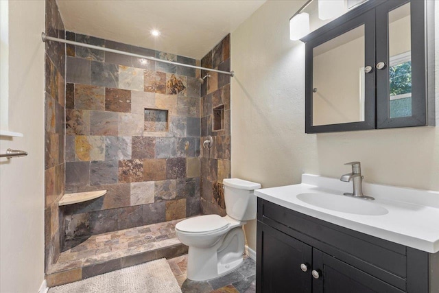 bathroom featuring vanity, toilet, and tiled shower