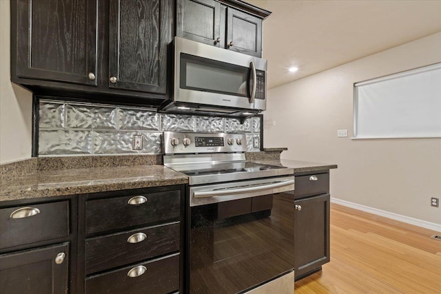 kitchen featuring light wood-type flooring, appliances with stainless steel finishes, and dark stone counters