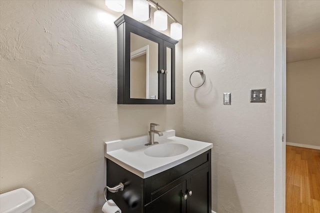 bathroom with vanity, wood-type flooring, and toilet