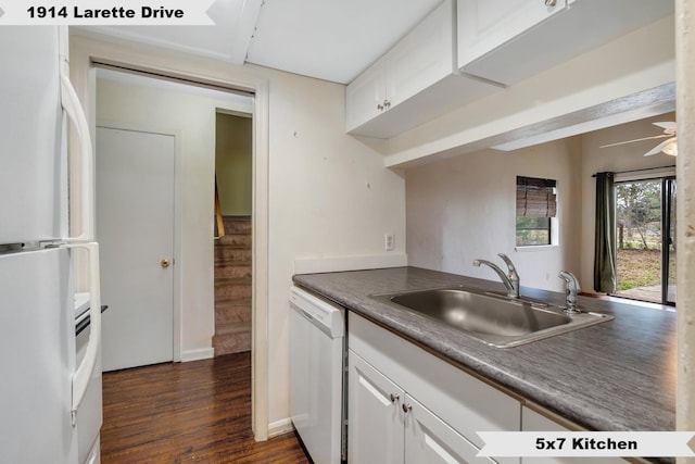 kitchen with white appliances, dark wood finished floors, dark countertops, white cabinetry, and a sink