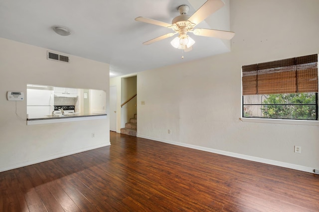 unfurnished room with dark wood finished floors, visible vents, ceiling fan, baseboards, and stairs