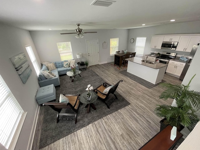 living area with a wealth of natural light, visible vents, and dark wood finished floors