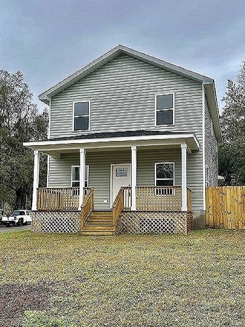 view of front facade featuring covered porch, fence, and a front yard