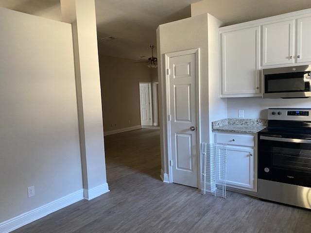 kitchen featuring light stone counters, dark wood-type flooring, white cabinets, and appliances with stainless steel finishes