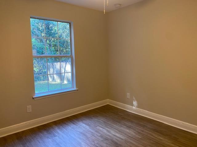 empty room with a wealth of natural light and dark wood-type flooring