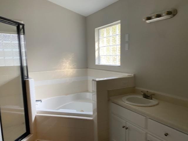 bathroom featuring tiled tub and vanity