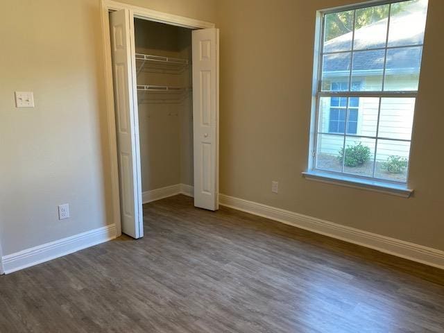 unfurnished bedroom with dark hardwood / wood-style floors and a closet