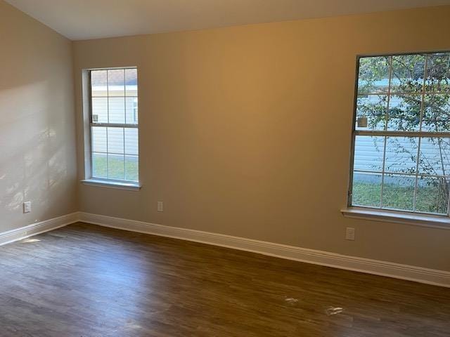 unfurnished room featuring dark wood-type flooring and plenty of natural light