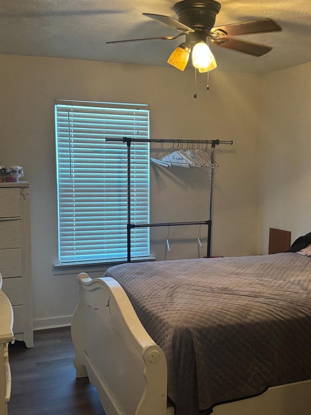 bedroom with ceiling fan, a textured ceiling, baseboards, and wood finished floors