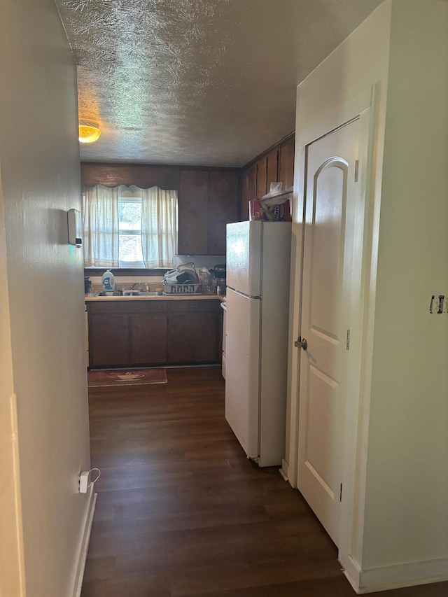 kitchen with dark wood-style floors, freestanding refrigerator, and a textured ceiling