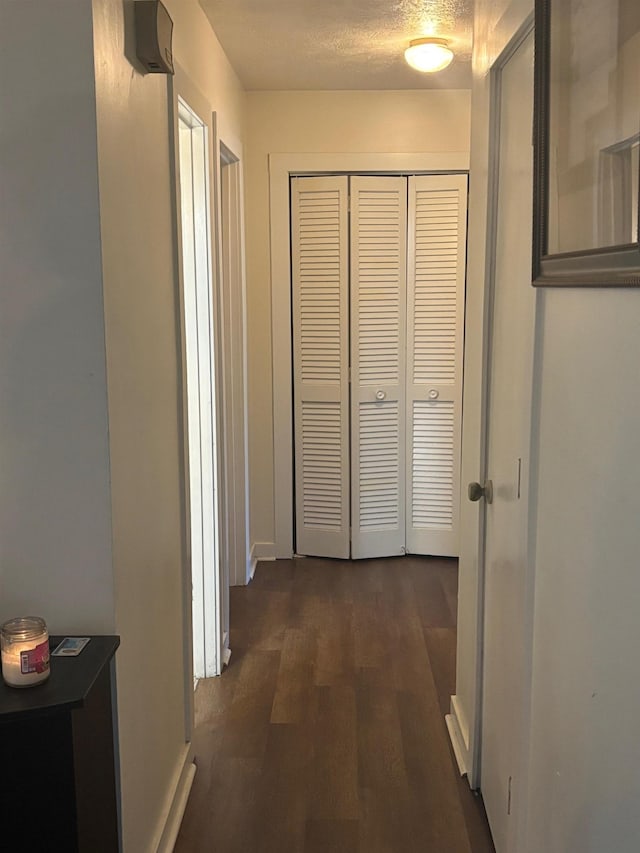 hallway featuring dark wood-style flooring and a textured ceiling