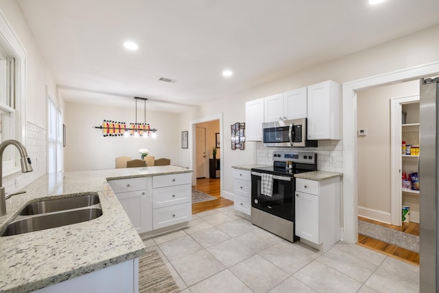 kitchen featuring stainless steel appliances, decorative light fixtures, sink, and white cabinets