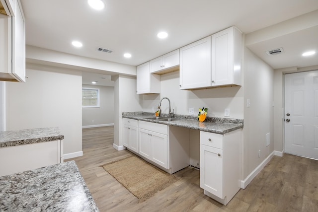 kitchen featuring white cabinetry, sink, and light wood-type flooring