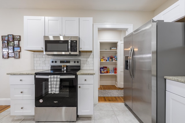 kitchen with white cabinetry, tasteful backsplash, light stone countertops, and appliances with stainless steel finishes