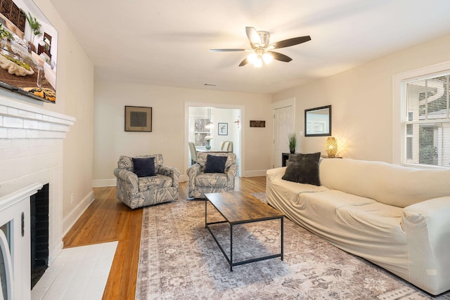 living room featuring a brick fireplace, hardwood / wood-style flooring, and ceiling fan