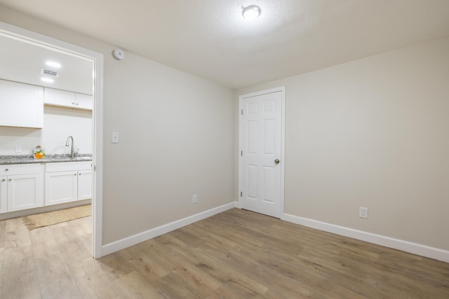 unfurnished room with sink and light hardwood / wood-style flooring