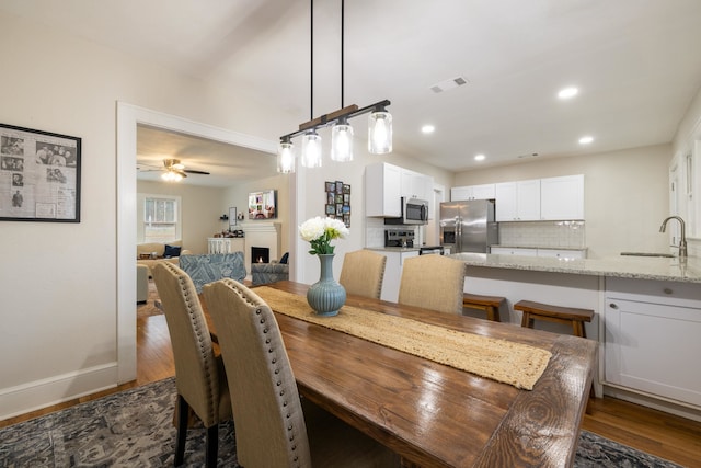 dining room featuring dark wood-type flooring, ceiling fan, and sink