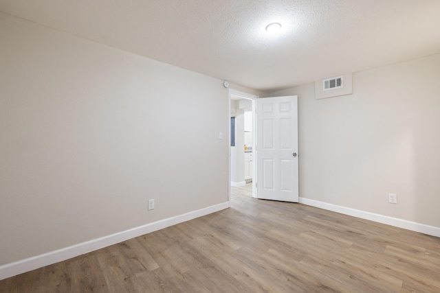 unfurnished room with light hardwood / wood-style flooring and a textured ceiling