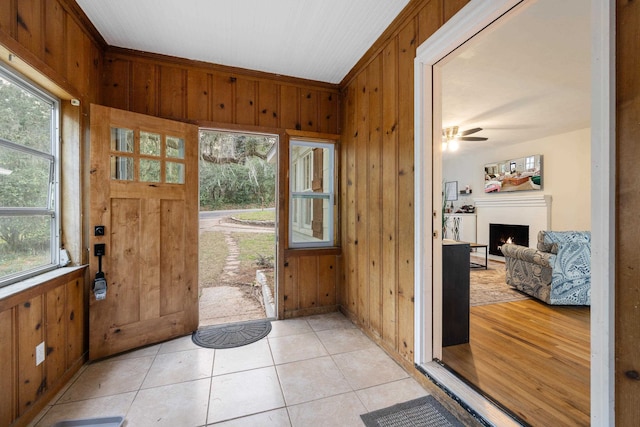 entryway with light tile patterned flooring, plenty of natural light, and wood walls