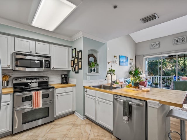 kitchen with white cabinetry, appliances with stainless steel finishes, and wooden counters