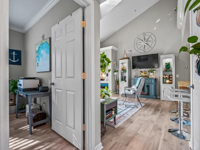 interior space with ornamental molding, vaulted ceiling, and light hardwood / wood-style floors