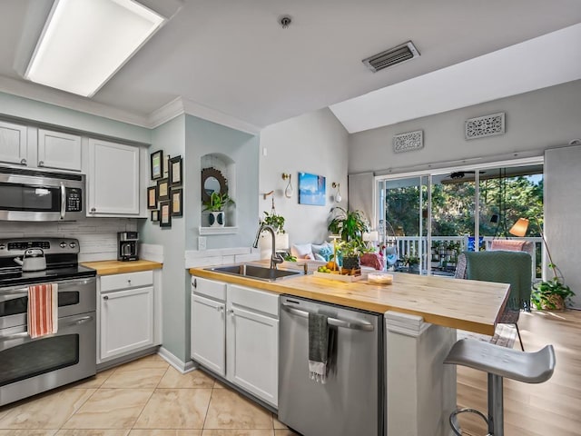 kitchen featuring wood counters, appliances with stainless steel finishes, sink, and white cabinets