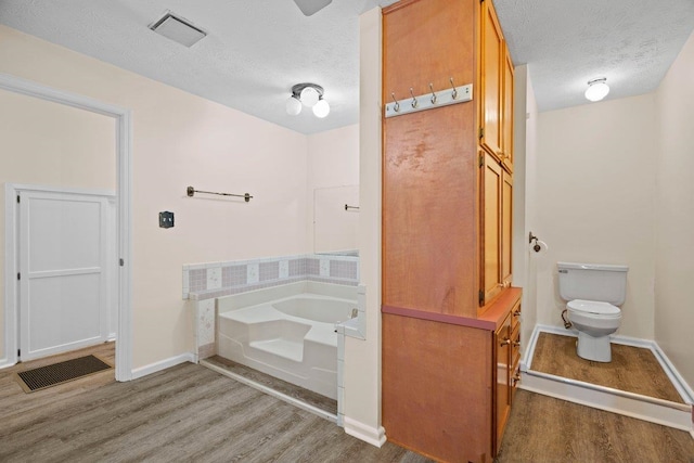 131 Alma Yates St, Quincy, FL 32351 - bathroom with wood finished floors, a textured ceiling, baseboards, a garden tub, and toilet