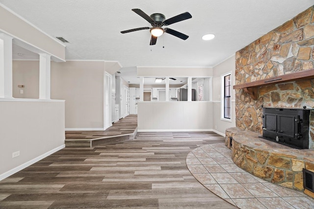 131 Alma Yates St, Quincy, FL 32351 - unfurnished living room featuring wood finished floors, ceiling fan, baseboards, a wood stove, and a textured ceiling