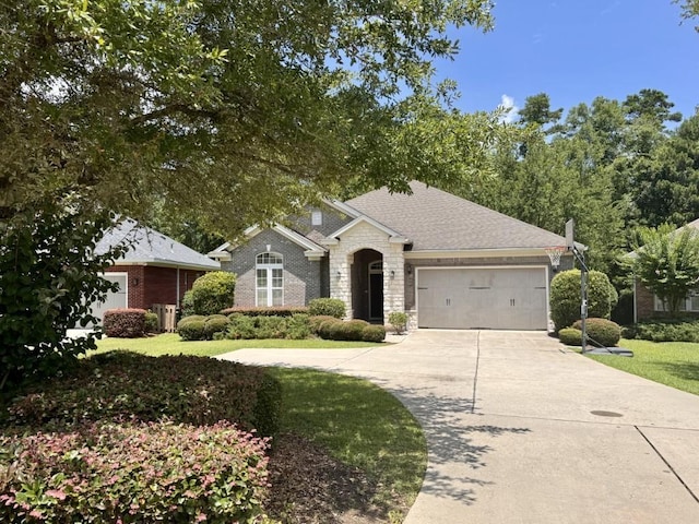 5672 Burnside Cir, Tallahassee, FL 32312 - view of front facade with a garage, driveway, stone siding, a front lawn, and roof with shingles