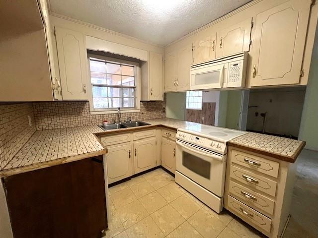 kitchen with sink, white appliances, backsplash, a textured ceiling, and kitchen peninsula