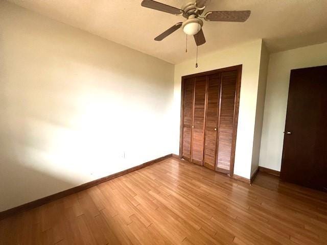 unfurnished bedroom featuring hardwood / wood-style floors, a closet, and ceiling fan