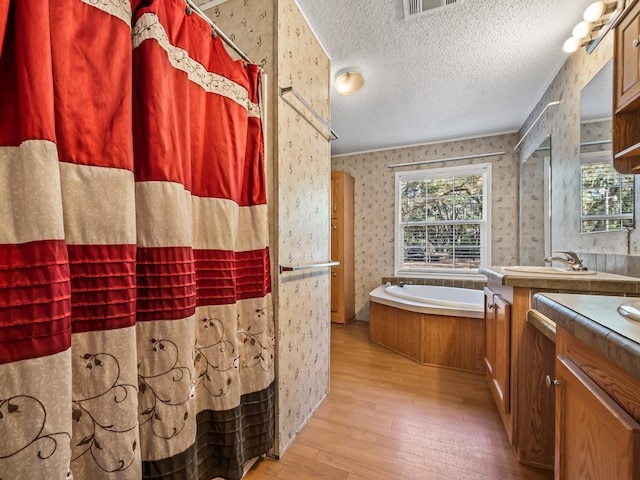 bathroom featuring a healthy amount of sunlight, vanity, hardwood / wood-style floors, and a textured ceiling