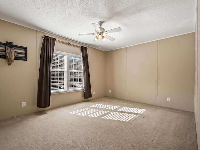 carpeted empty room featuring ceiling fan and a textured ceiling