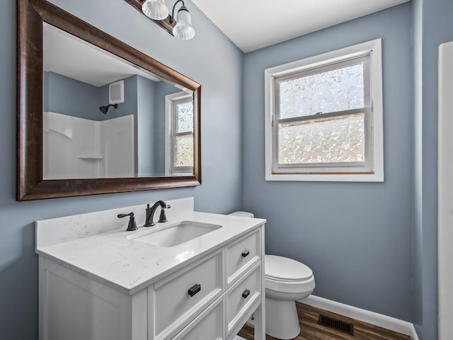 bathroom featuring vanity, wood-type flooring, walk in shower, and toilet