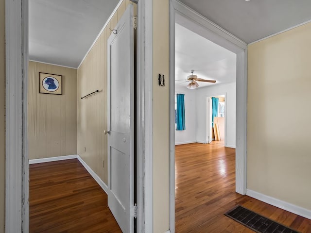 hall with wood-type flooring and wooden walls