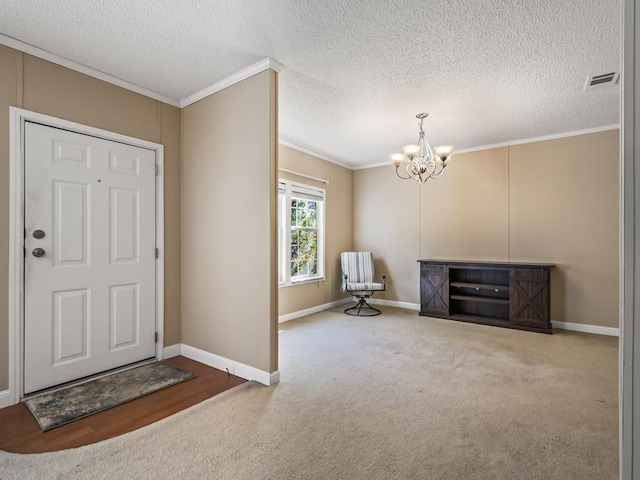 carpeted entrance foyer with ornamental molding, a textured ceiling, and an inviting chandelier