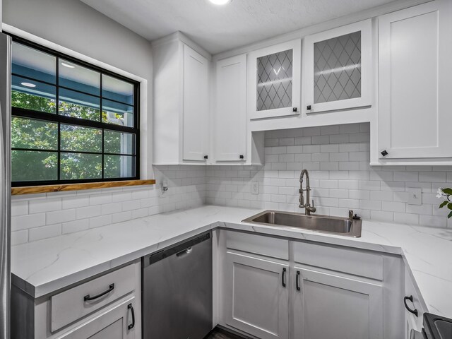 2600 Panther Creek Rd Unit A, Tallahassee, FL 32308 - kitchen featuring stainless steel dishwasher, decorative backsplash, white cabinets, light stone countertops, and glass insert cabinets