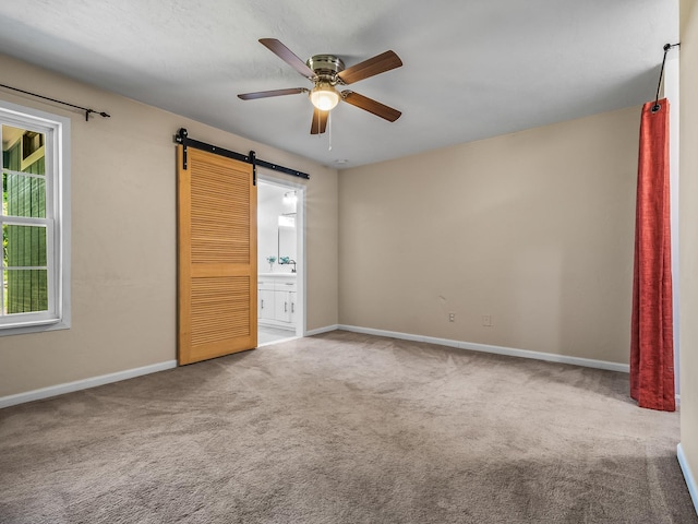 2600 Panther Creek Rd Unit A, Tallahassee, FL 32308 - unfurnished bedroom featuring a barn door, carpet floors, connected bathroom, and a ceiling fan