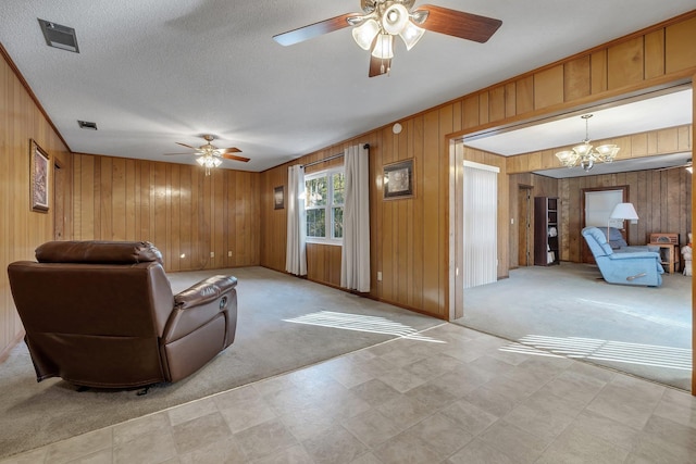 carpeted living room featuring a textured ceiling, ceiling fan with notable chandelier, and wooden walls