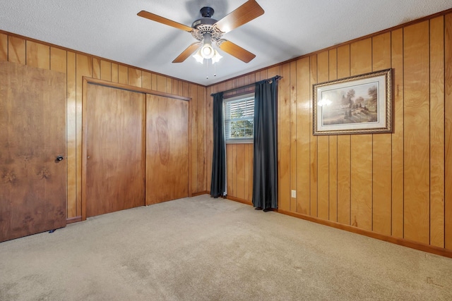 unfurnished bedroom with ceiling fan, light colored carpet, a textured ceiling, and a closet