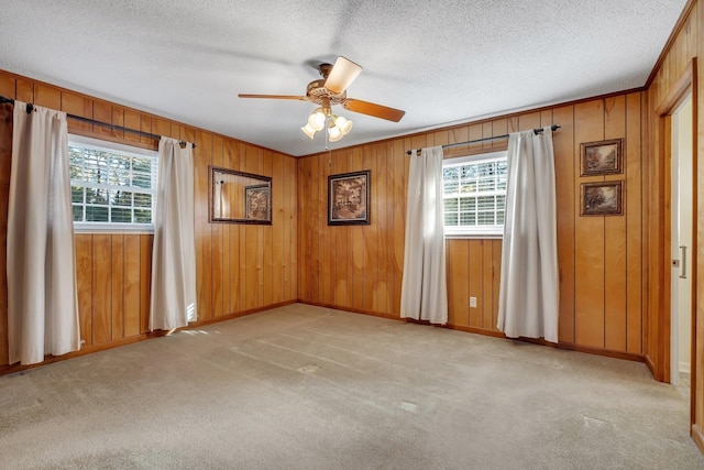 empty room featuring ceiling fan, a healthy amount of sunlight, light colored carpet, and a textured ceiling