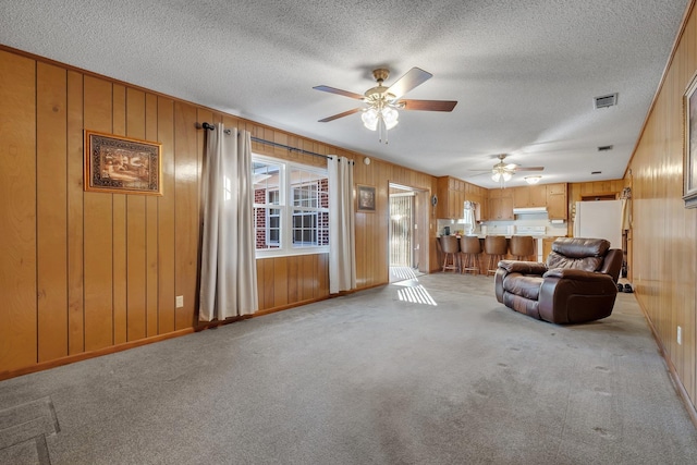 living room with ceiling fan, a textured ceiling, and light carpet