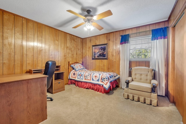 carpeted bedroom with ceiling fan, wooden walls, and a textured ceiling