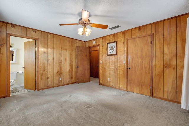 unfurnished bedroom with ceiling fan, light colored carpet, and ensuite bath