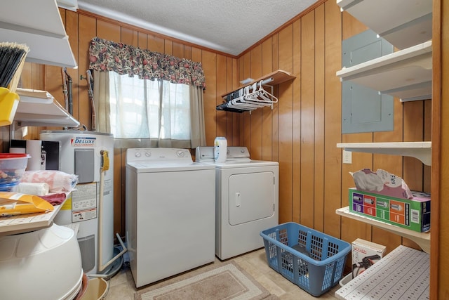 laundry area with water heater, a textured ceiling, washing machine and clothes dryer, and wooden walls