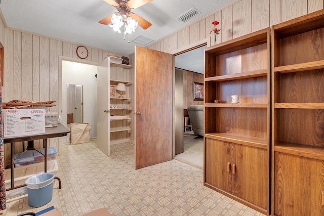 kitchen with ceiling fan and wooden walls