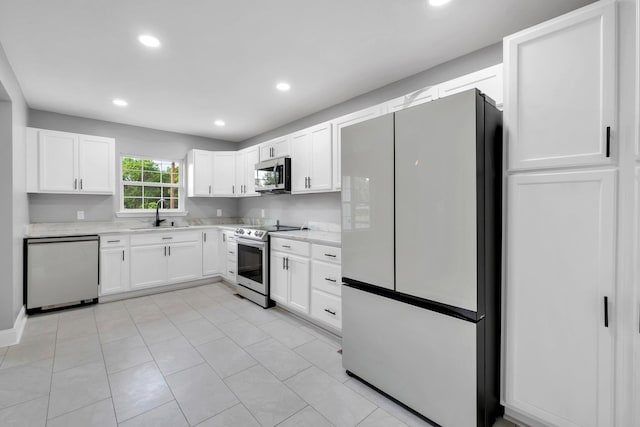 kitchen with stainless steel appliances, white cabinetry, sink, and light tile patterned floors