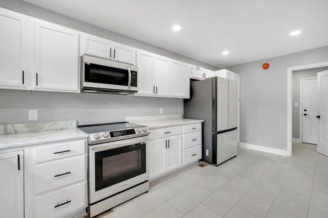 kitchen featuring stainless steel appliances, light stone countertops, white cabinetry, and light tile patterned flooring