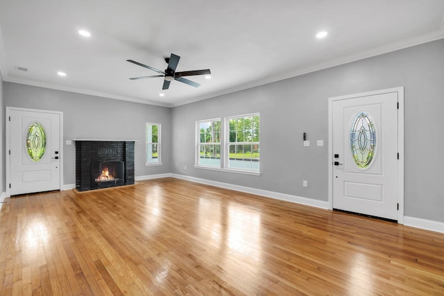 entrance foyer with light wood-type flooring, ornamental molding, and a brick fireplace